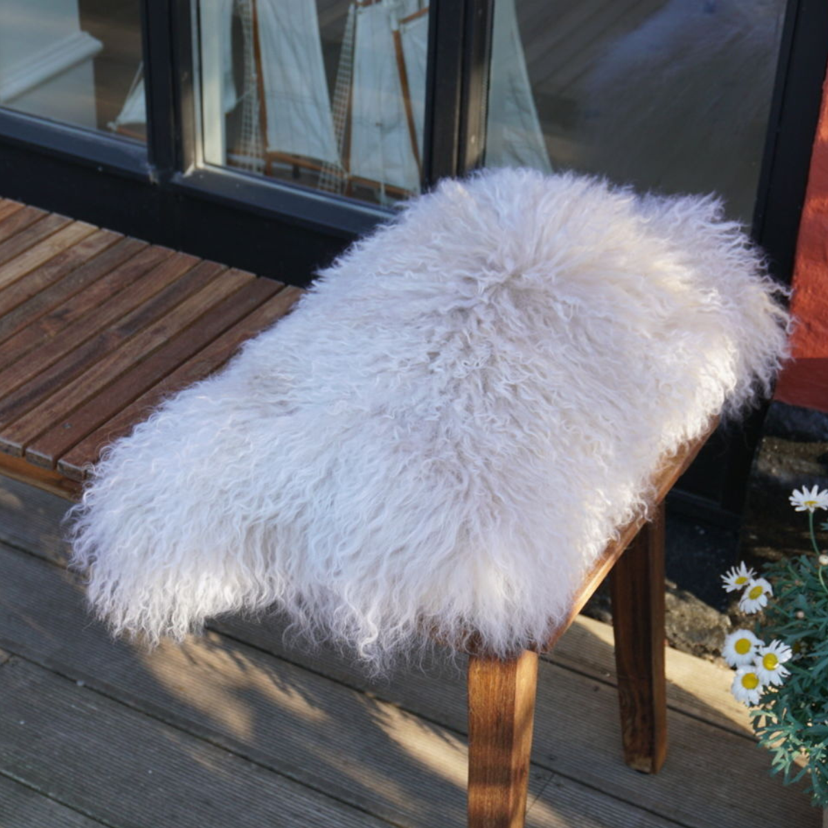 Weisses lockiges Lammfell auf eine Holzbank