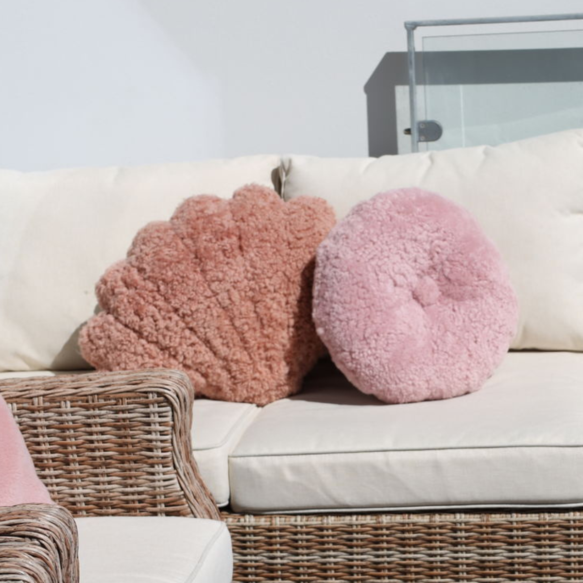 Zwei rosafarbene Fellkissen auf ein Sofa