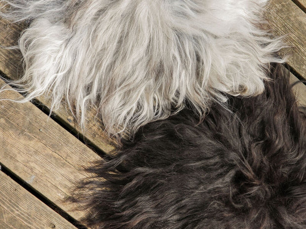 ein weisses und ein schwarzes schaffell auf holzdielen